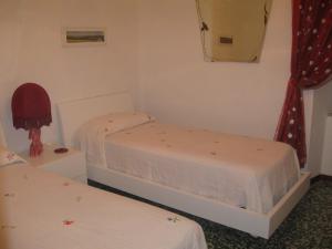 two beds in a small room with red curtains at Affittacamere Casa Delle Rose in Antria