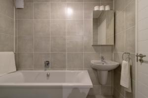 a bathroom with a tub and a sink at #AlimamaSpaces Jade's Greenlee in Sandton +33 photos