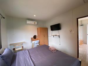 a bedroom with a bed and a tv on the wall at Fran Sim Da Guest House in Bang Tao Beach