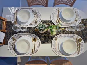 a table with plates and glasses on a table at Modern Stay at Seri Kembangan - 20 mins to Pavilion Bukit Jalil in Seri Kembangan