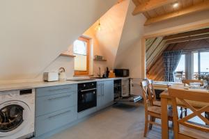 a kitchen with a washer and dryer next to a table at Apartamenty Tatra Loft in Ząb