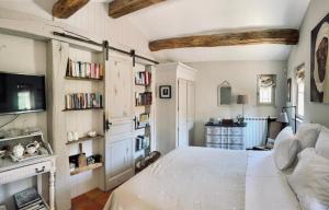 a bedroom with a large white bed and bookshelves at Le Mas de la Rose in Taradeau