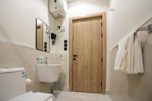 a bathroom with a toilet and a wooden door at Aljood Residence-BY CH in Al Madinah +45 photos