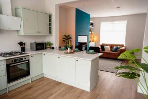 a kitchen with white cabinets and a living room at Above Rubies - Sawley Cottage, Canal, Cafes, Bars! in Skipton