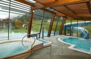 a large indoor swimming pool with a large window at Luxury B&B August in Ortisei