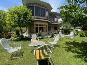 um grupo de cadeiras sentadas na grama em frente a uma casa em Flora Inn Skardu em Skardu