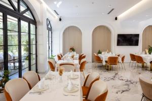 ein Restaurant mit weißen Tischen und Stühlen und großen Fenstern in der Unterkunft Chimaera Hotel in Himarë