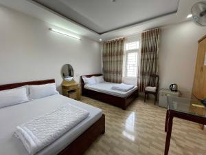 a bedroom with a bed and a desk and a window at Khách sạn Đông Tây Quy Nhơn in Quy Nhon