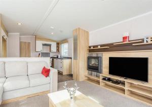 Una sala de estar con un sofá blanco y un televisor de pantalla plana. en Sanctuary 10 Hot tub lodge, en Fort Augustus