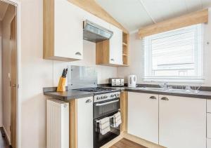 Una cocina con gabinetes blancos y un horno de estufa. en Sanctuary 10 Hot tub lodge, en Fort Augustus