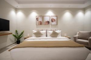 a bedroom with a large white bed and a chair at Aljood Residence-BY CH in Al Madinah