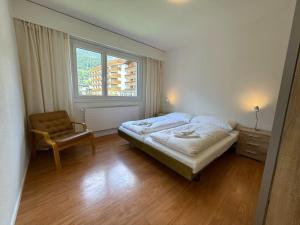 a bedroom with a bed and a chair and a window at Mayenzett 34 in Leukerbad