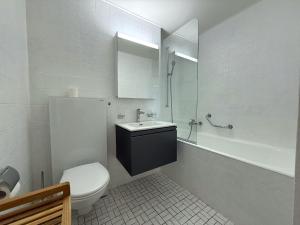 a white bathroom with a toilet and a sink at Mayenzett 34 in Leukerbad +38 photos