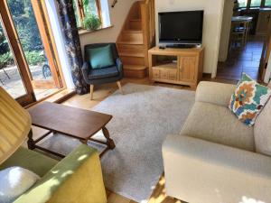 a living room with a couch and a tv at Fig Tree Cottage 