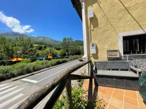 a balcony of a building with a bench and a road at La Casina del Arroyo in Poo de Cabrales