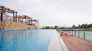 a swimming pool with benches on the side of a building at Swiss-Belvillas Solavita Binh Tien in Binh Tien