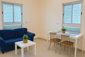 a living room with a blue couch and a table and chairs at Revava Country Stay in Migdal Afeq