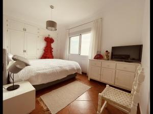 Un dormitorio blanco con una cama y un televisor. en Montaña Mimosa, en Alhaurín el Grande