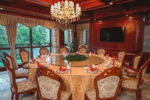 a dining room with a table and chairs and a television at Liuchunwu Resort in Tianmu Mountain in Menkou