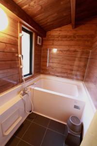 ein Bad mit einer Badewanne in einem Zimmer mit Holzwänden in der Unterkunft Kitakaruizawa Sweet Grass - Vacation STAY 82370v in Kita-karuizawa