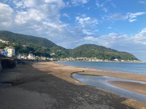 a sandy beach with mountains in the background at IG3 Oyado Sankan Shion - Vacation STAY 61821v in Ito