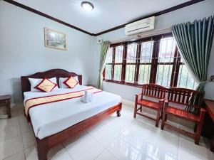 a bedroom with a bed and a chair and windows at Khampaseuth Hotel in Vang Vieng