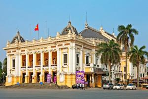 a yellow and white building with palm trees in front of it at Oh Trendy Homes Hoan Kiem PNL3 in Hanoi