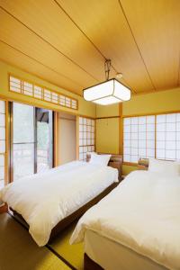 two beds in a room with yellow walls and windows at Sansuien "Michi" - Rental villa with hot spring - - Vacation STAY 54071v in To-katta
