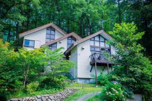 ein weißes Haus mit Balkon im Wald in der Unterkunft Miyama - Zao Sansuien Gaia Resort - Vacation STAY 54108v in To-katta