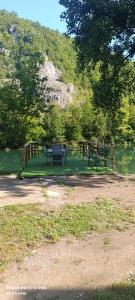a picnic table and benches in a park next to a lake at Faris in Bihać