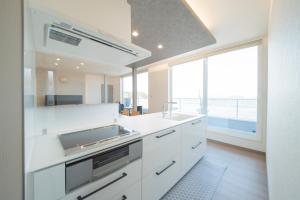 a kitchen with white cabinets and a large window at Guest House Aji Nakaniwa - Vacation STAY 17513 in Takamatsu