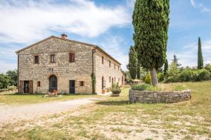 an old stone building in a field with a tree at Tenuta Podere Montemelino in Sarteano