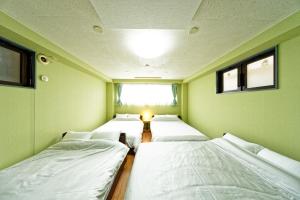 a row of four beds in a room with a window at TwinB Building 5 Haruoka 2F - Vacation STAY 17506 in Nagoya