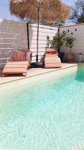 two lounge chairs and an umbrella next to a swimming pool at La maison de Mona in Carcassonne