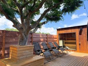 a group of chairs sitting on a deck next to a tree at Otomie Log House - Vacation STAY 69931v in Kimitsu