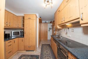 Una cocina con gabinetes de madera y una encimera negra. en Haus Elisabeth Top 108, en Krimml 7 fotos más