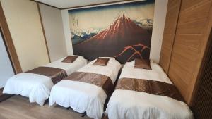 eine Gruppe von vier Betten in einem Zimmer mit einem Gemälde in der Unterkunft Hida Takayama Kandamachi House - Vacation STAY 88763v in Takayama