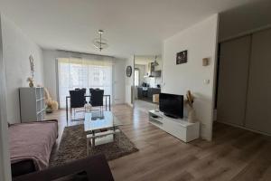 a living room with a couch and a tv at Apartment with balconies close to beaches in Caen