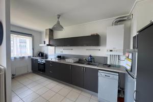 a kitchen with black and white cabinets and appliances at Apartment with balconies close to beaches in Caen