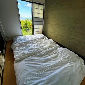 an unmade bed in a room with a window at Sky Sauna Kukai - Vacation STAY 97168v in Kumamoto
