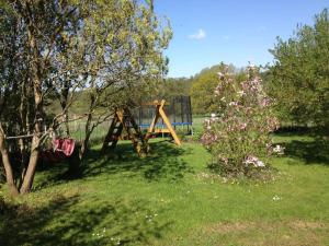 a playground in a field with a tree and flowers at Ferienhaus "Landhaus Speck" Objekt-ID 12131-6 in Speck