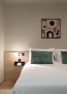 a bedroom with a bed with white sheets and green pillows at Gnamma Hotel in Athens