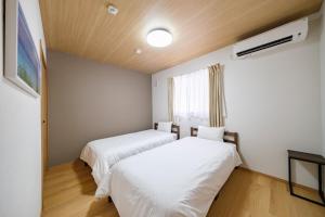 two beds in a room with white sheets and a window at BLUESOLARE Reef - Vacation STAY 14123v in Miyako Island