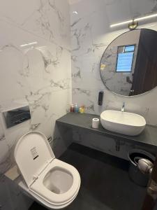 a bathroom with a toilet and a sink and a mirror at Cozy 3BHK Villa with a Private Lawn - Karjat in Dhamni