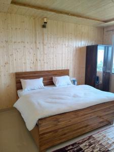 a large bed in a room with wooden walls at Kanatal Majestic Resort by RIHS in Kanatal