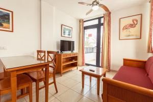 a living room with a couch and a table and a tv at Oasis Playa Maspalomas in Maspalomas