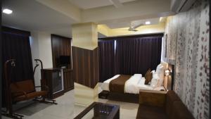 a bedroom with a bed and a couch and a tv at Hotel Royal Residency in Vadodara