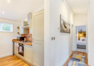 Sanctuary Caledonia Hot tub lodge في حصن أوغسطس: مطبخ مع دواليب بيضاء وسرير في الغرفة