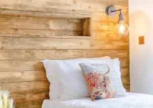 Sanctuary Caledonia Hot tub lodge في حصن أوغسطس: غرفة نوم بجدار خشبي مع وسادة بقرة