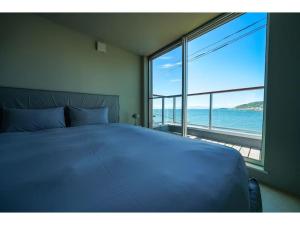 a bedroom with a bed and a view of the ocean at &SUN mini mini - Vacation STAY 17824 in Yokosuka